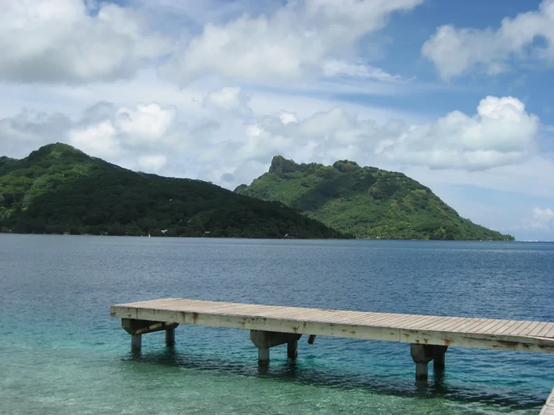 Le ponton et les reliefs verdoyants face à la baie de Fare à Huahine.