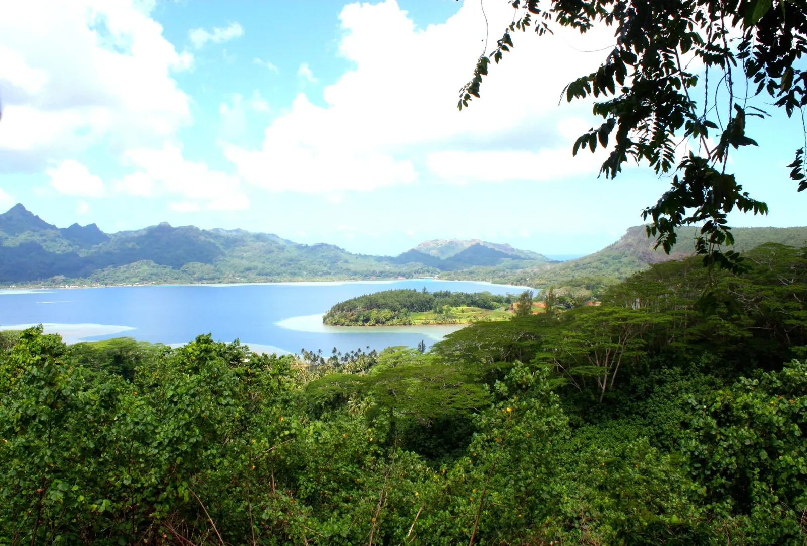 La baie de Maroe et ses rives montagneuses, vues à travers les arbres depuis un belvédère de Huahine.