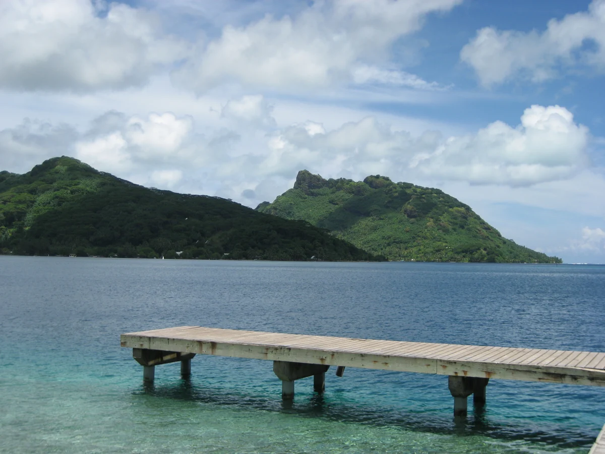 Le ponton et les reliefs verdoyants face à la baie de Fare à Huahine.