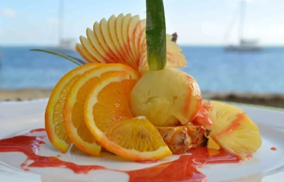 Un dessert glacé accompagné de fruits, avec le lagon en arrière-plan, au restaurant du Mahana.