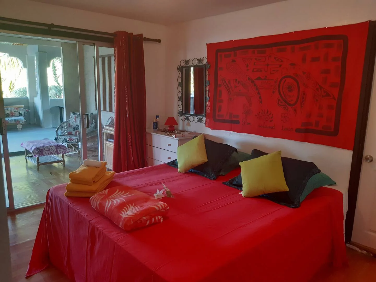 Chambre avec lit double et couvre-lit rouge à la Pension Poe Huahine