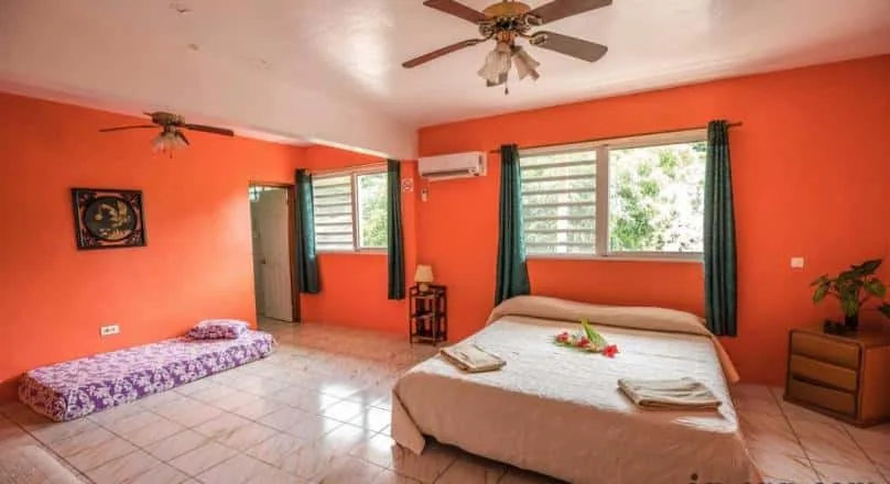 Chambre orange avec lit double et lit simple à Poetaina