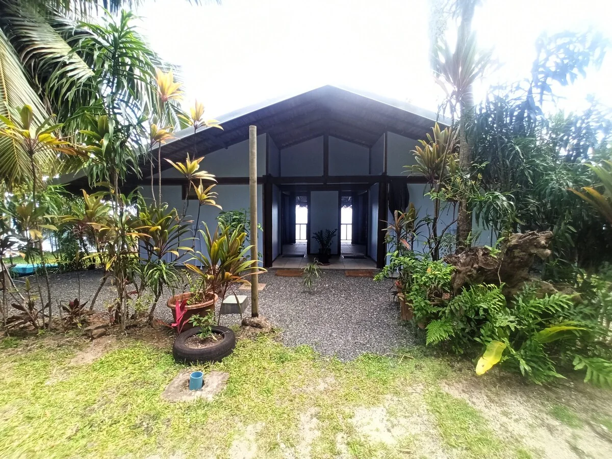Entree cote jardin du bungalow Te Nahe Toetoe, entouree de plantes tropicales.