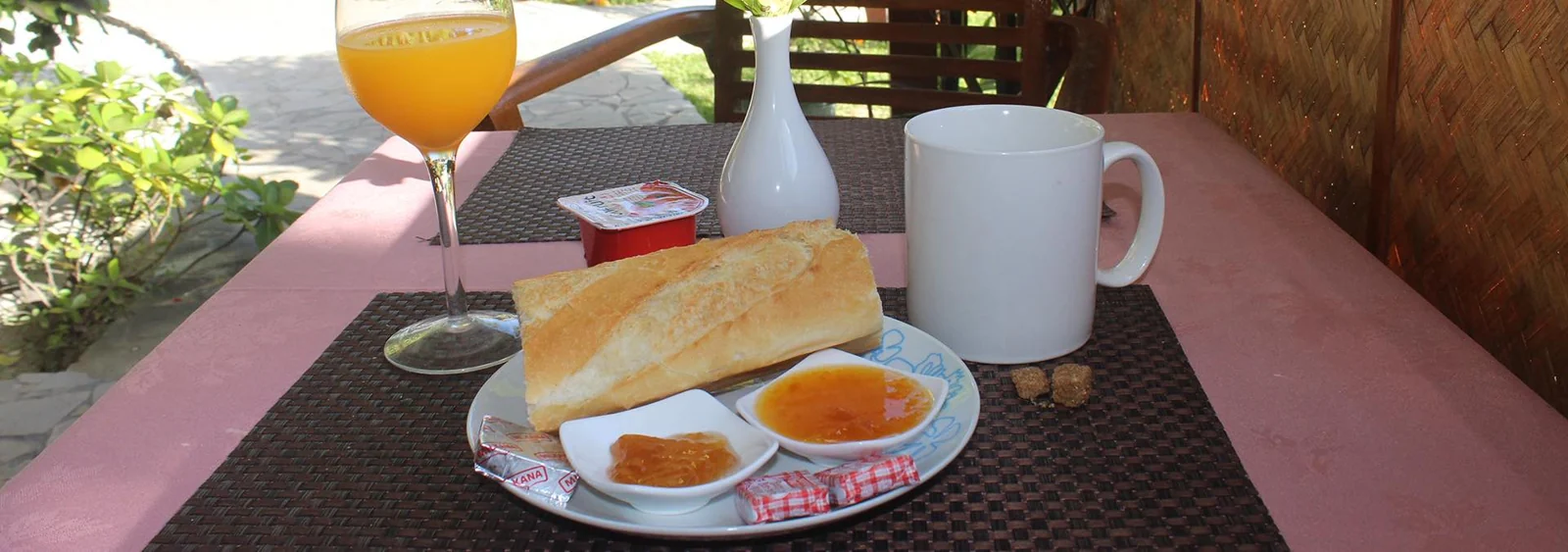 Petit déjeuner avec pain, confitures, tasse et jus de fruits sur une table du restaurant Tehina.