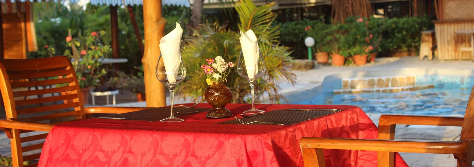 Une table dressée sous la terrasse du restaurant Tehina avec la piscine à l’arrière-plan.
